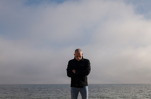 Adult man on beach holding jacket against sea and sky. Almeria, Spain