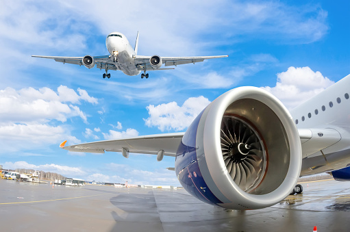 View of the wing and engine of a passenger aircraft and a landing airplane flying in the sky