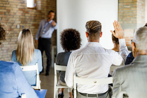 istock Back view of businessman asking a question on a seminar in board room. 1367786941