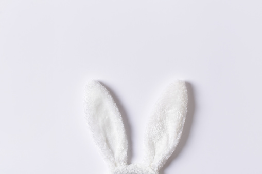 Happy easter concept with white bunny ears on grey background, copy space, top view, minimalism