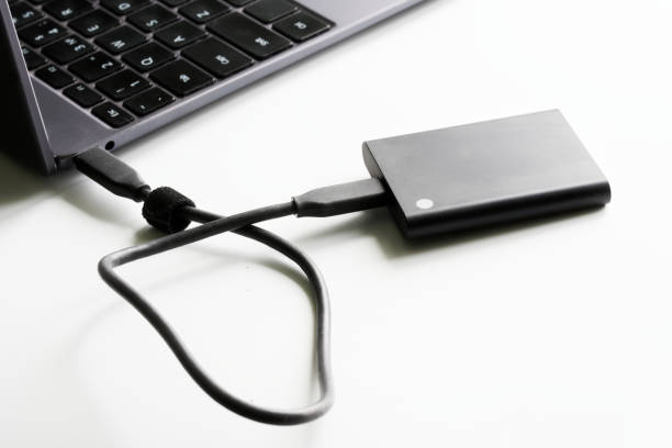 istock External high-speed portable SSD is connected to a laptop or ultrabook. White background. Portable Solid State Drive. The concept of using modern gadgets. Storing digital data 1367788146