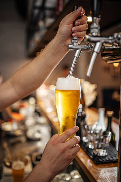 Hands pouring draught beer into a glass Bartender's hands pouring draught beer into a glass beer pump stock pictures, royalty-free photos & images