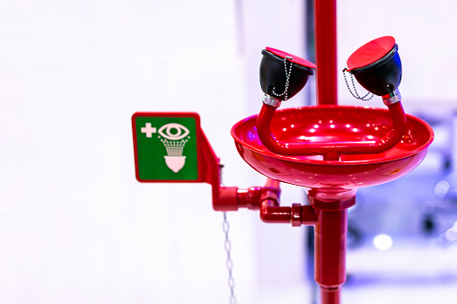 Red emergency eye washing station equipment with safety signage unit for chemical accident or critical
