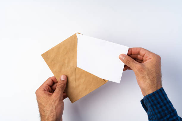 istock Top view of male hands hold (open) an envelope above white background 1367793075