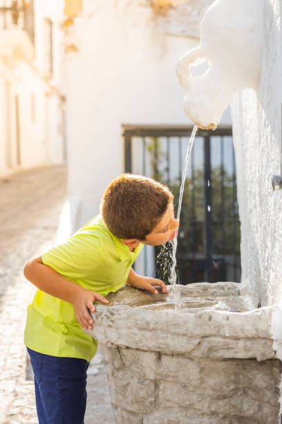 istock Thirsty kid drinking of an ancient fountain 1367795309