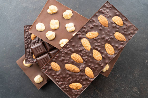 istock Chocolate bars with walnuts a tower on a black background. Milk and Dark Chocolate With Almonds and Hazelnuts Isolated 1367796225