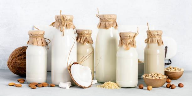 istock Non dairy plant based milk in bottles and ingredients on light background. Alternative lactose free milk substitute, banner 1367796595