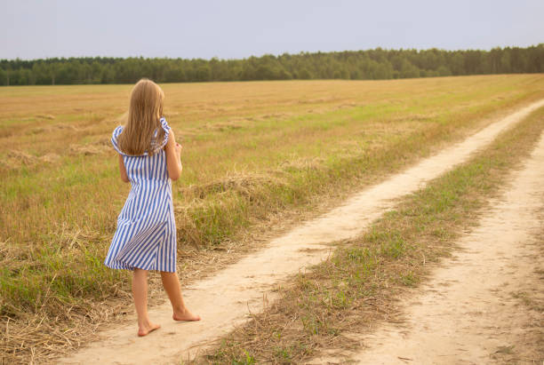 istock girl go on path in field 1367797623