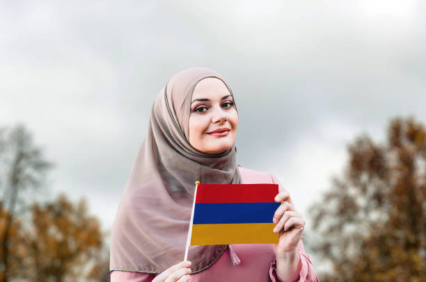 ヒジャーブのイスラム教徒の女性は、アルメニアの旗を保持しています - armenian ethnicity ストックフォトと画像
