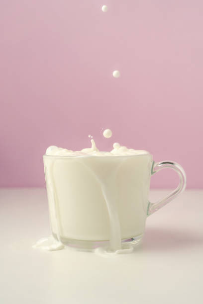istock Milk is poured into a transparent cup on a purple background. 1367800369