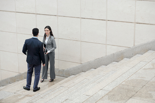 Positive business colleagues standing outdoors and discussing work details