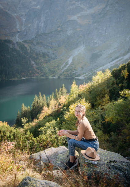 istock Young woman on a hiking trip sitting on a rock 1367803610