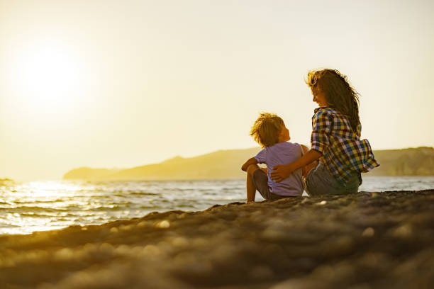 istock Happy single mother and son talking on the beach at sunset. 1367805006