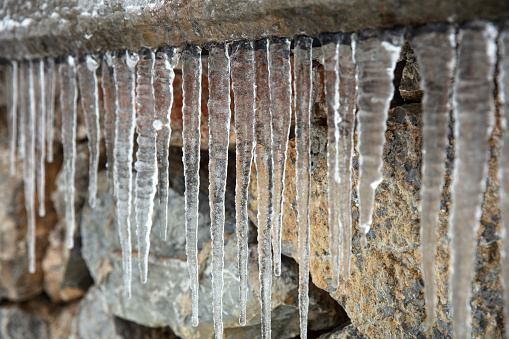 Large group of icicles on stone wall background