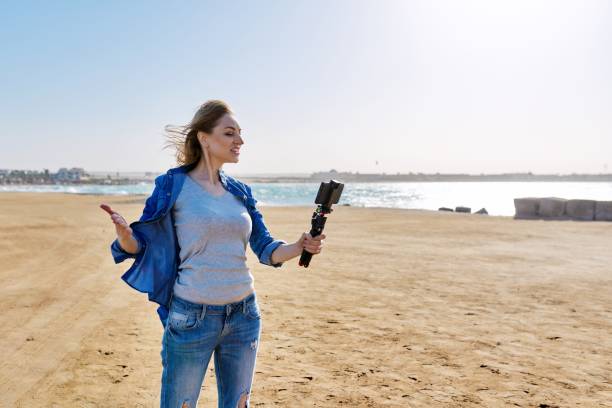 istock Middle aged woman on the beach talking online using smartphone. 1367809369