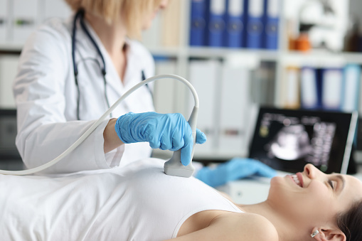 Médico que realiza un examen de ultrasonido de la mama de la paciente en la clínica photo