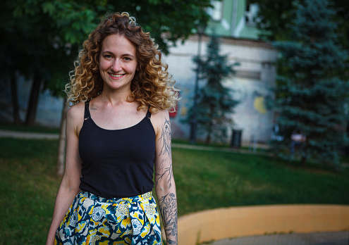 A curly-haired cute woman with tattoos on the street