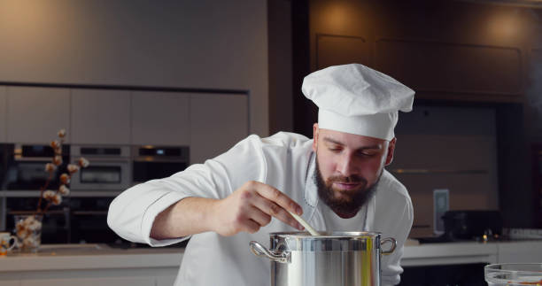 istock Professional chef stirring soup with spoon in restaurant kitchen 1367817264