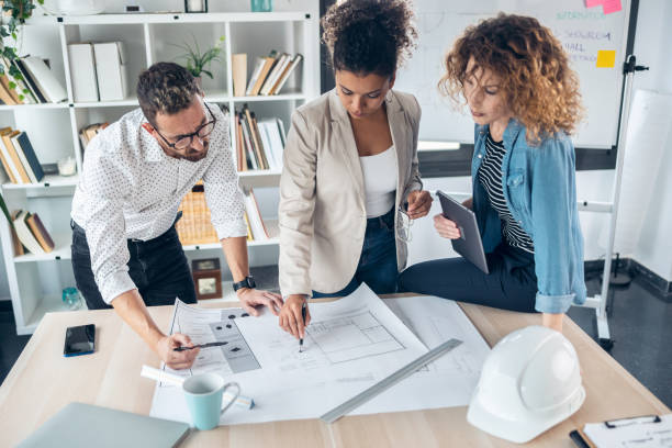 istock Smart architects working with plans while talking of their new design business in the office. 1367817822