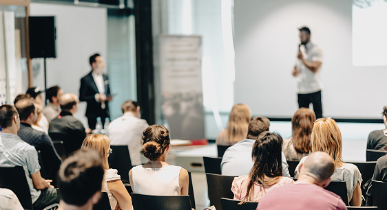 Young businesswoman entering and showing directions to business people during seminar