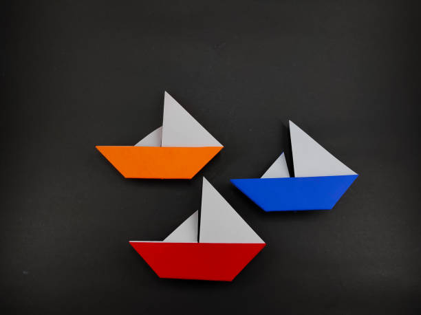 Origami sailing ship in three colors isolated on black background