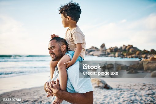 istock Shot of a man carrying his son on his shoulders at the beach 1367820788