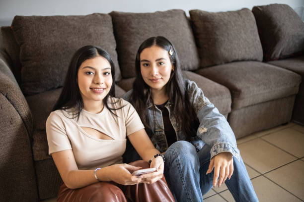 istock Portrait of sisters using smartphone at home 1367822153