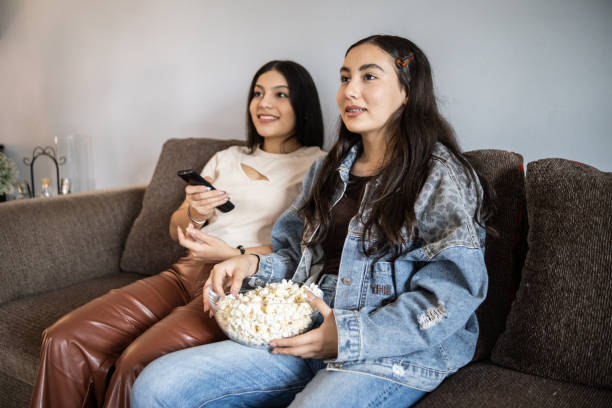 istock Sisters watching movie and eating popcorn at home 1367822178