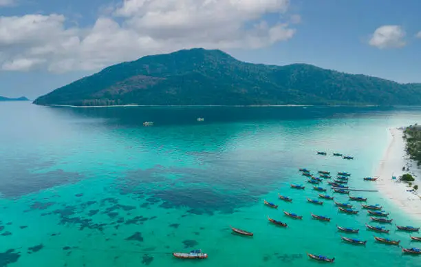 Aerial view of the Tropical island beach with seashore as the tropical island in a coral reef ,blue and turquoise sea with local boat background