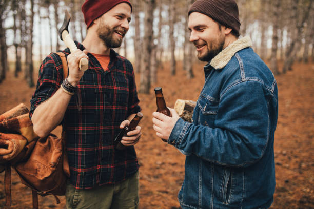 istock Two millennial man hiking and drinking beer in a forest, laughing and having fun. 1367823792
