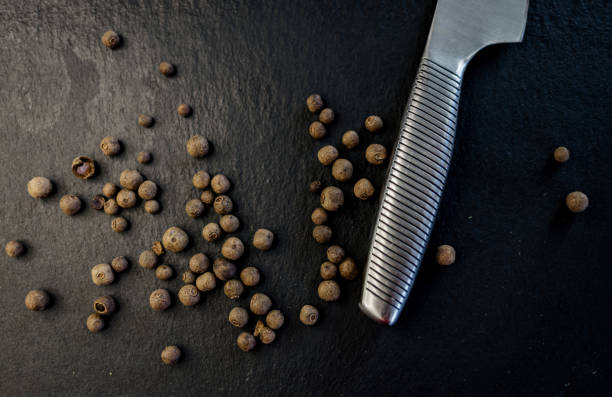 schwarze pfeffersamen und messer - directly above macro pepper black peppercorn stock-fotos und bilder