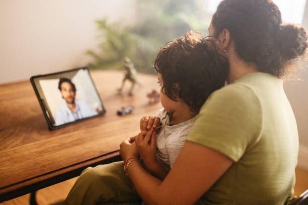 Mother and child video calling their family doctor at home Mother and child video calling their family doctor on a digital tablet. Mother and son having an online consultation with their paediatrician. Loving young mother caring for her sick son at home. telemedicine stock pictures, royalty-free photos & images