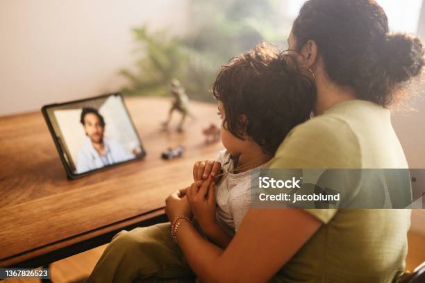 Mother And Child Video Calling Their Family Doctor At Home Stock Photo - Download Image Now