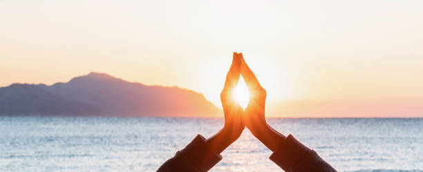 istock Closeup of hands in meditation pose with sun between them 1367828043
