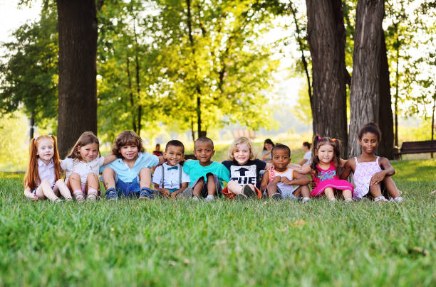many young children of different races play together in the Park on the green fresh grass stock photo