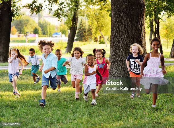 Eine Gruppe Von Vorschulkindern Die Auf Dem Rasen Im Park Laufen Stockfoto und mehr Bilder von Kind