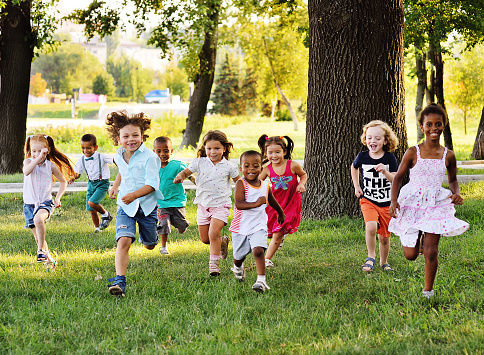 un grupo de niños en edad preescolar corriendo en el césped del Parque photo