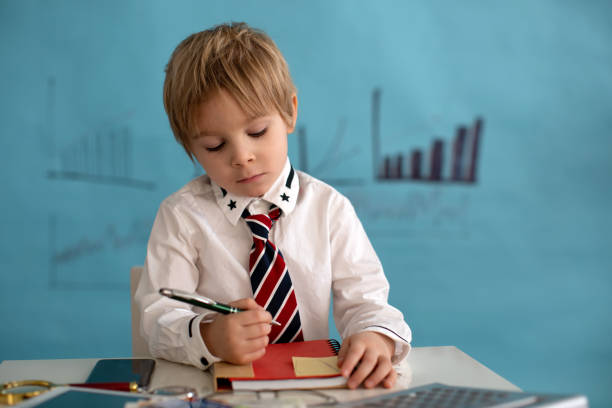 istock Good looking, smart casual dressed child, blond boy with tie, working on tablet, taking notes and talking on the phone, business concept 1367829733
