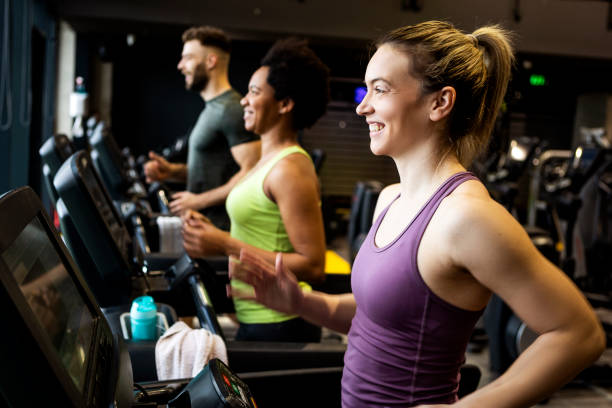 joven mujer sonriente corriendo en cinta de correr - gimnasio escolar fotografías e imágenes de stock