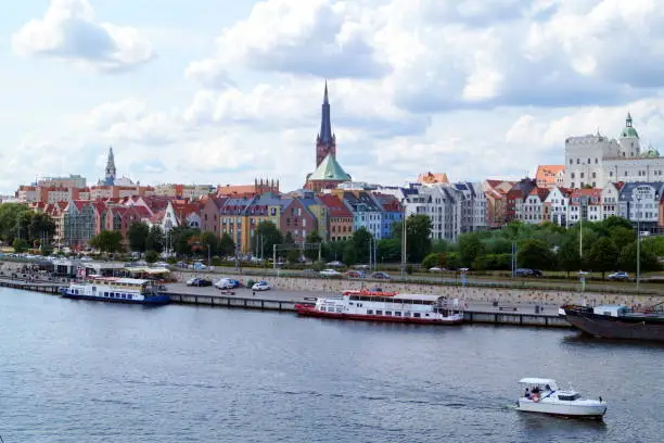 A beautiful view of the city of Szczecin - a panorama of the historical part of the city, the Odra River, on the pier of which there are ferries, ships, boats. Above the city a magnificent sunny sky with soft lush clouds