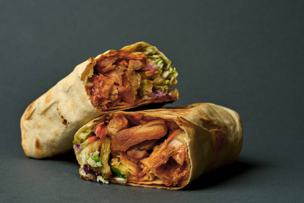 Large shawarma with meat and vegetables in a pita on a dark background. Selective focus, close-up stock photo