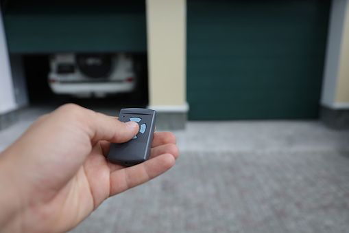Person opens the garage door in which the car is located with a remote control.