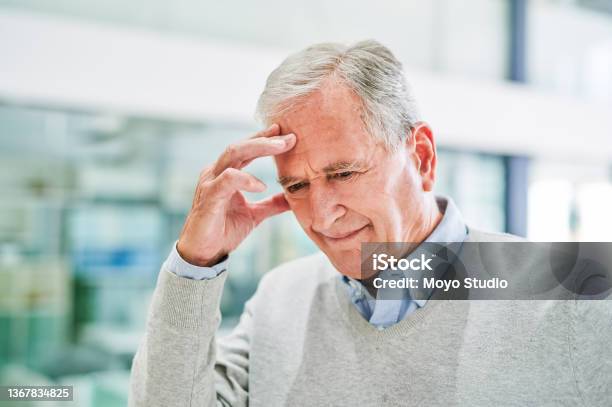 Shot Of A Senior Man Suffering From A Headache At A Clinic Stock Photo - Download Image Now