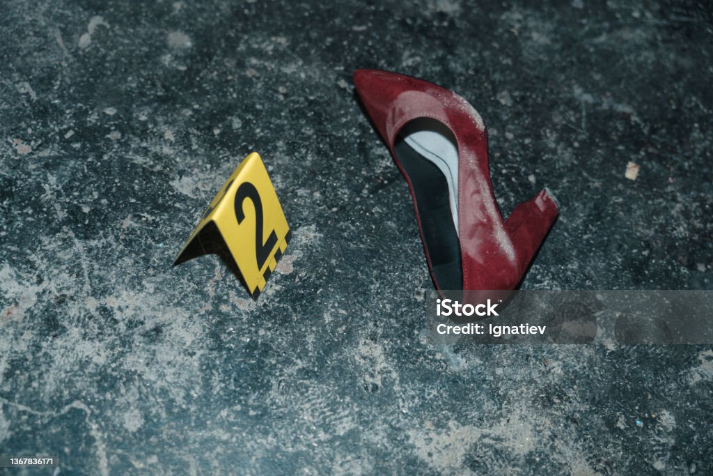 Red high heeled shoe on the floor at the crime scene from the high angle with yellow number next to it Red high heeled shoe on the floor at the crime scene from the high angle, illuminated by a flashlight Crime Scene Stock Photo