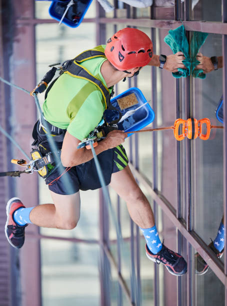 istock Industrial mountaineering worker cleaning window outside building. 1367837843