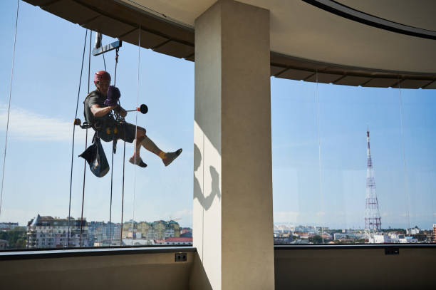 istock Industrial mountaineering worker cleaning window outside building. 1367837982