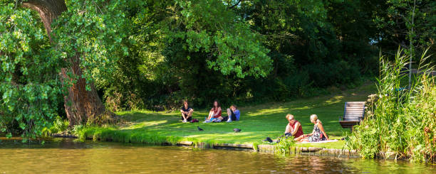 October 30th. 2023. Grand Union Canal at Hatton Locks Warwickshire England UK. It is a sunny day and the canal is still. Summer colours line the bank. There are narrow boat barges on the canal. A couple are walkingon the towpath.