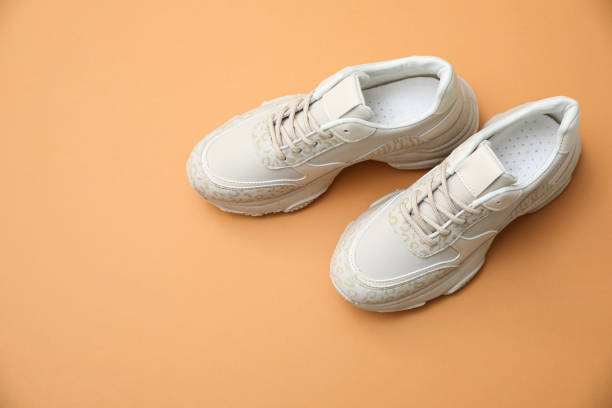 istock Stylish white shoes on pale orange background 1367838467