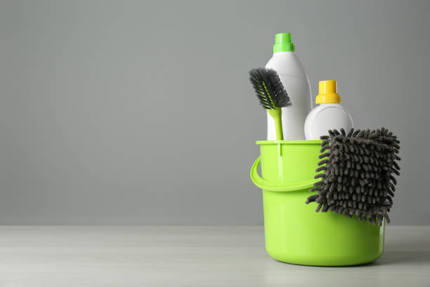 istock Bucket with cleaning products and tools on grey table. Space for text 1367841573
