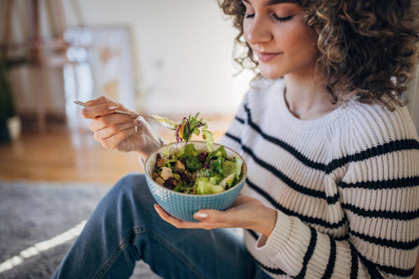 istock Young woman eating a salad 1367842974